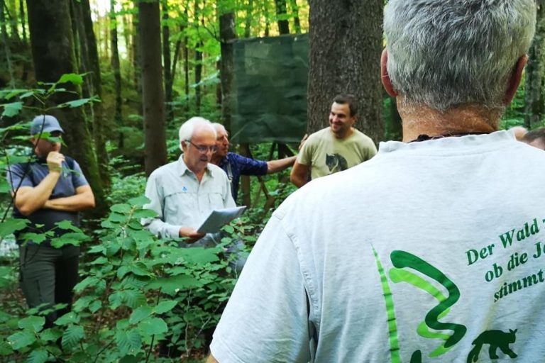 Im Wald erzählt ein Förster Besuchern etwas.