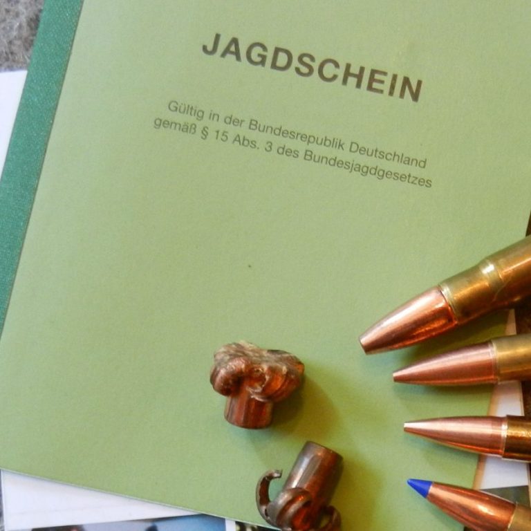 Auf einem Jagdschein liegen Geschossreste und drei Jagd-Kugelpatronen.